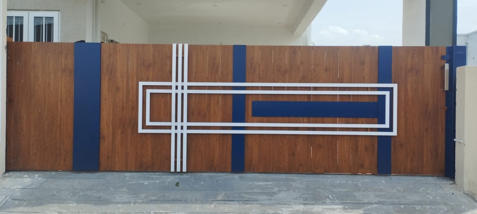 Custom sliding gate with wood-finish panels and navy blue geometric accents